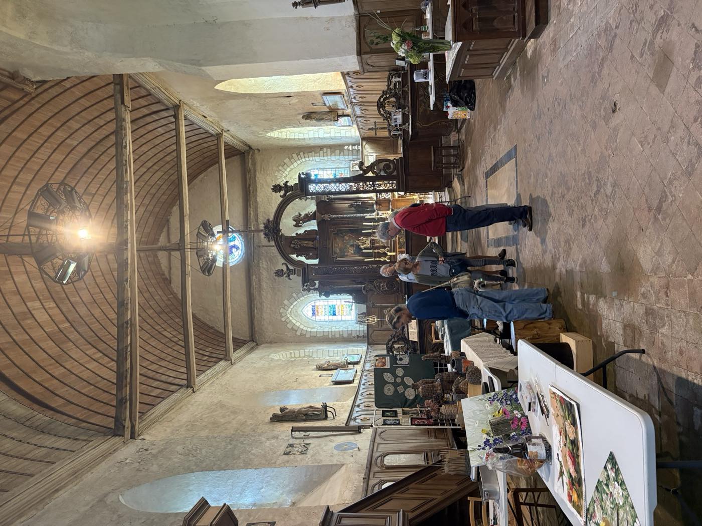 La nef vue vers l’entrée, les tables d’exposition alignées le long des boiseries sous la charpente en berceau.
