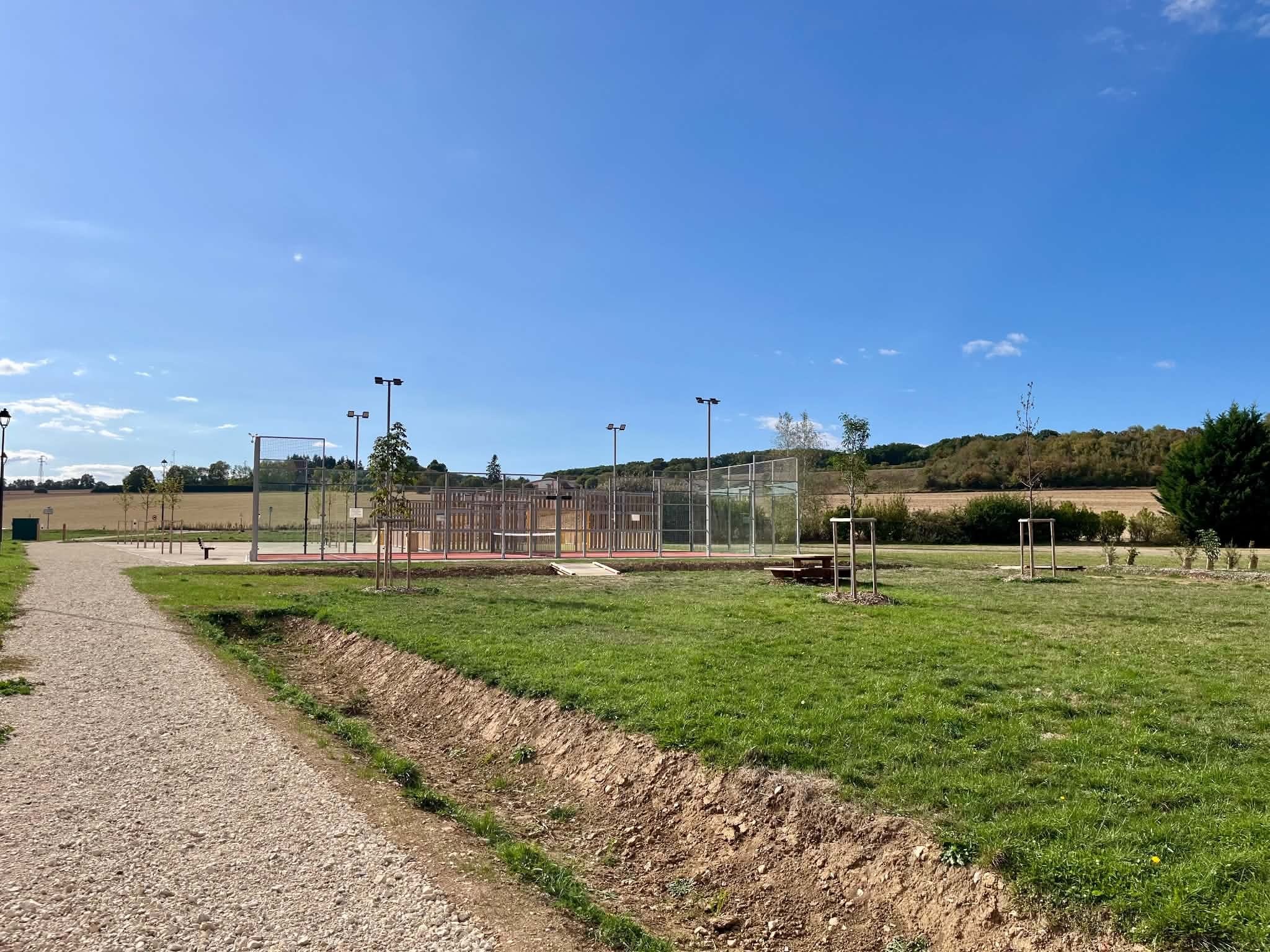 Un chemin du parc de Muzy, engazonné et bordé de prairie